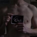 Photo of Freddy with a scan of the baby he is carrying.