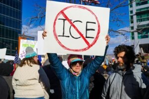 Protester holds sign with "no ice" symbol.